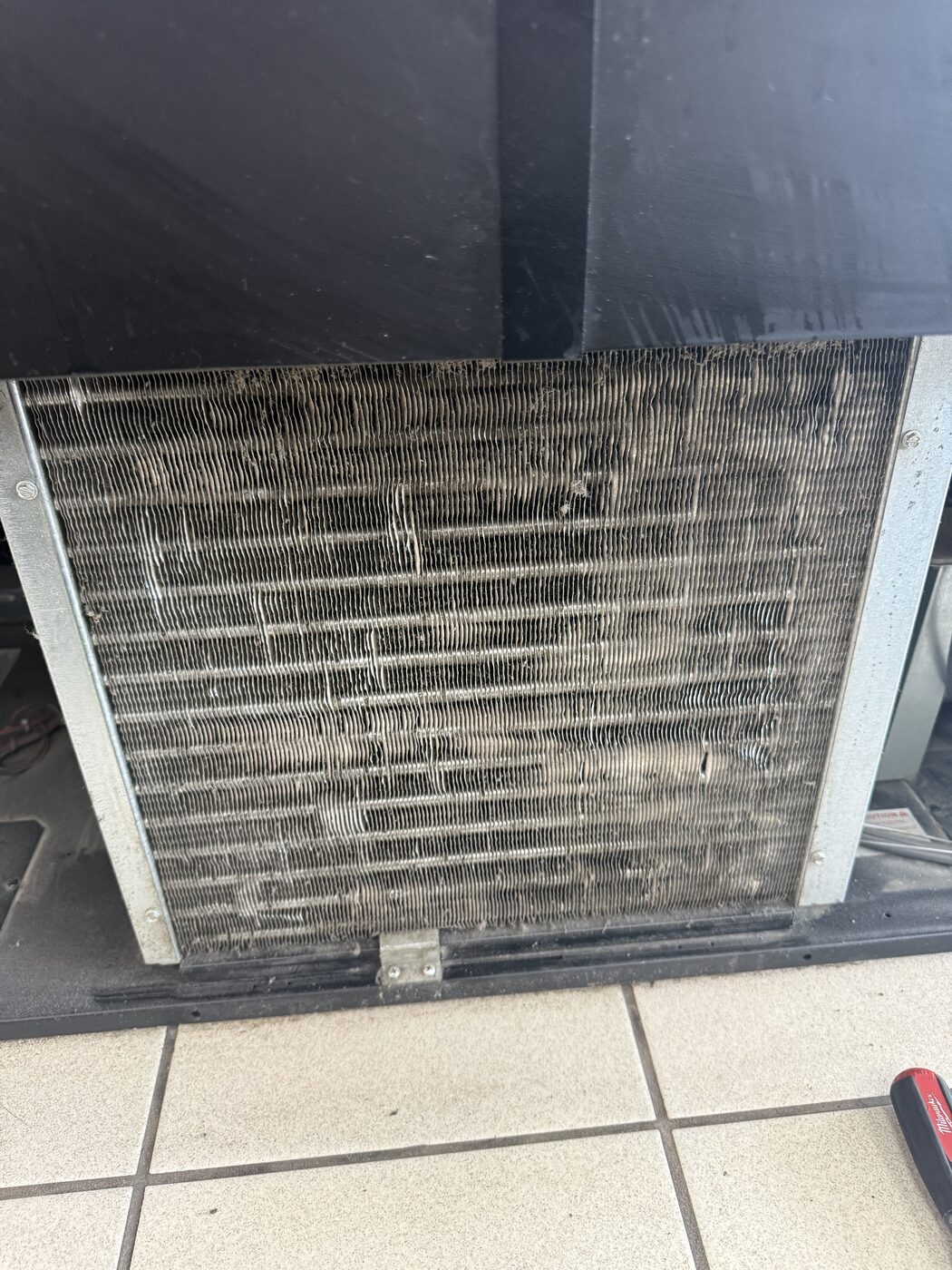 Dirty condenser coil with dust-laden fins on a commercial refrigeration unit