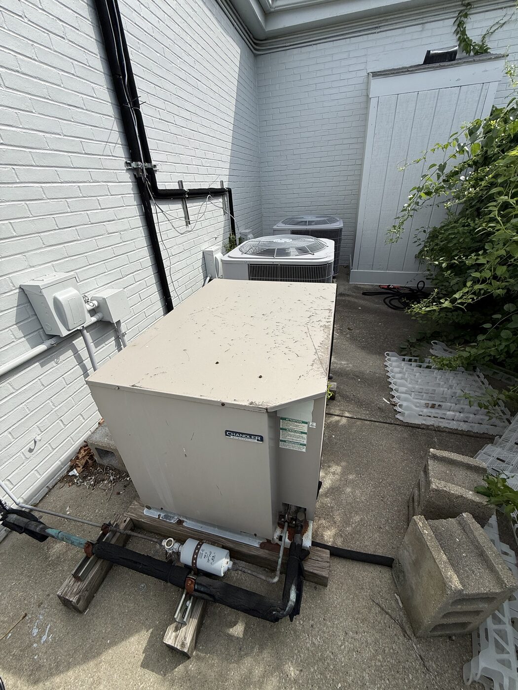 Outdoor packaged HVAC unit with exposed refrigerant piping in a side alley