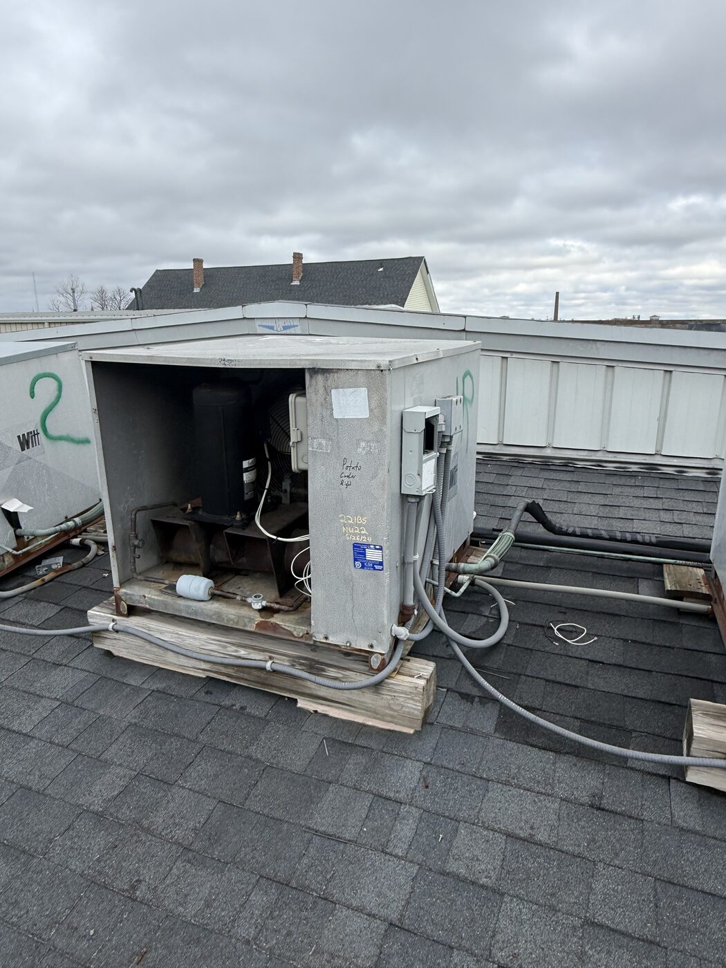 Rooftop commercial refrigeration condensing unit with access panel open exposing the compressor