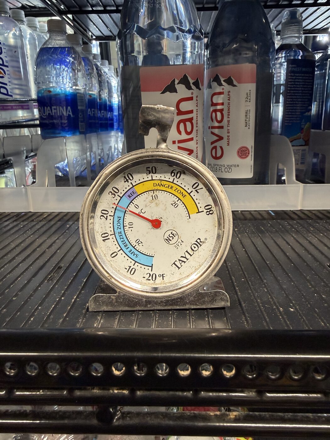 Taylor dial refrigerator thermometer reading safe temperature inside a stocked beverage cooler