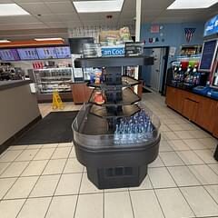 Open-top refrigerated beverage display case stocked with bottled water in a convenience store