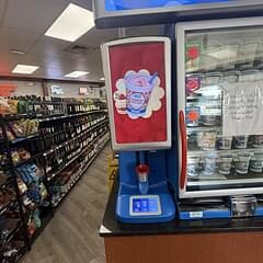 Convenience store frozen beverage dispenser and refrigerated display cooler in a retail aisle