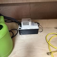Condensate removal pump installed beneath a commercial refrigeration unit to manage drain water