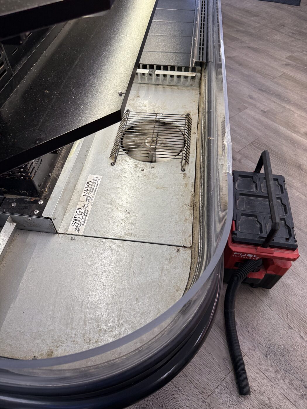 Evaporator fan guard and base deck inside a deli display case during maintenance