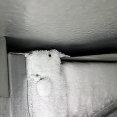 Frozen evaporator coil edge with heavy snow-like frost accumulation inside a commercial freezer