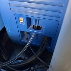 Lower service panel of a blue commercial refrigeration unit with drain and electrical lines